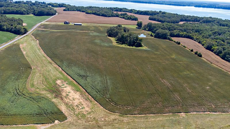 Aerial of open farmland running down to a lake