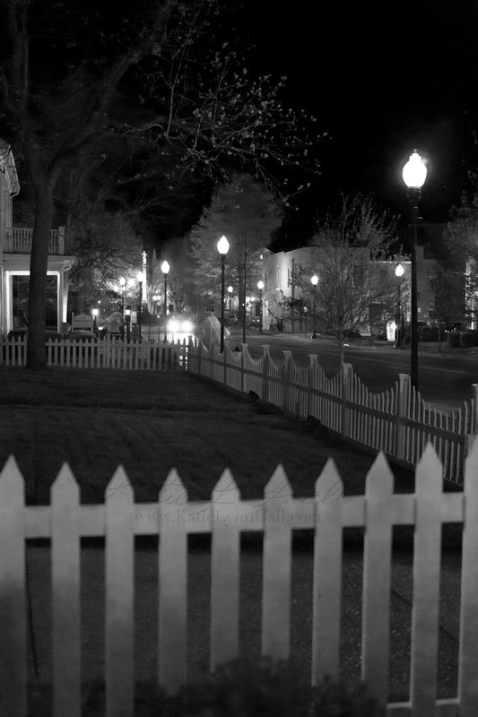 White picket fence and street lamps at night