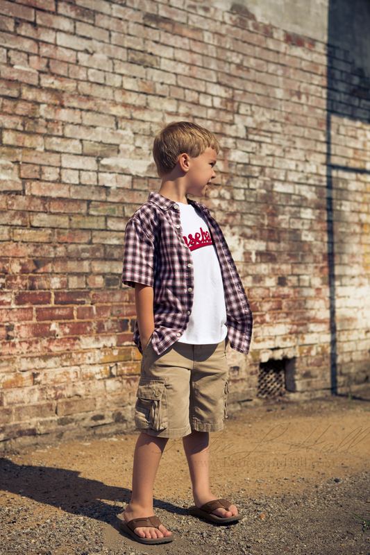 Young boy in a plaid shirt against an old brick wall