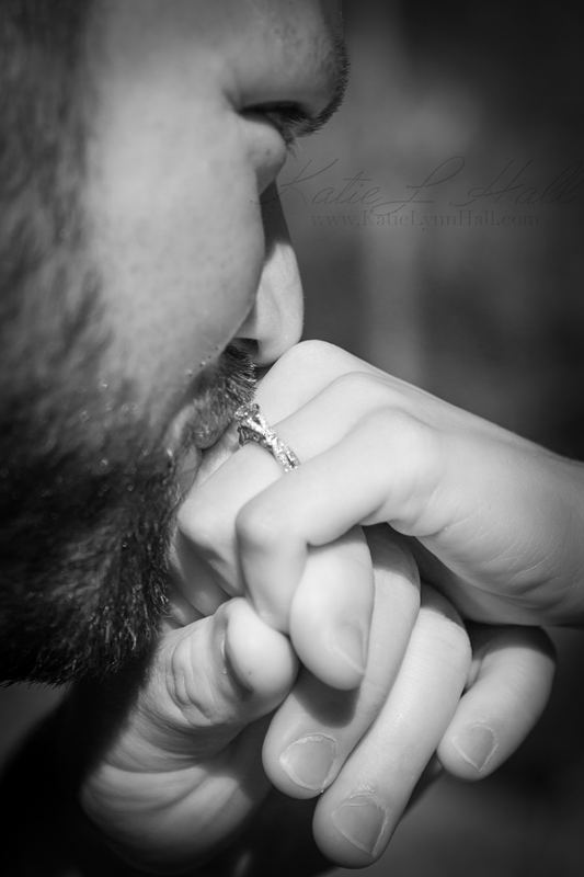 Black and white close-up of a groom kissing his bride’s hand