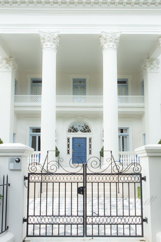 Grand white columned home behind a wrought-iron gate